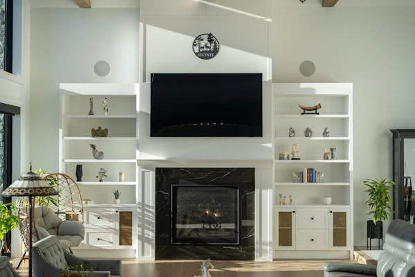 Example photo: built-in white shelving and cupboards either side of a fireplace with a TV above