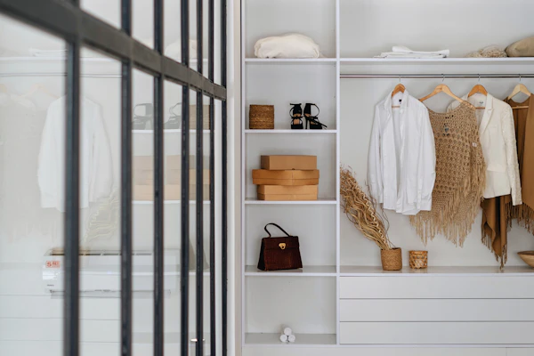 Example photo: open white wardrobe shelving with hanging clothes and storage boxes